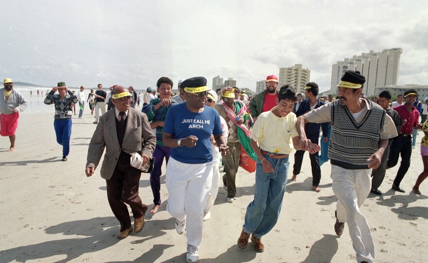 Desmond Tutu (center) jogs along a Whites-only beach with a crowd of supporters at the Strand in South Africa in 1989 as church organizations continued their campaign of defiance against apartheid laws.