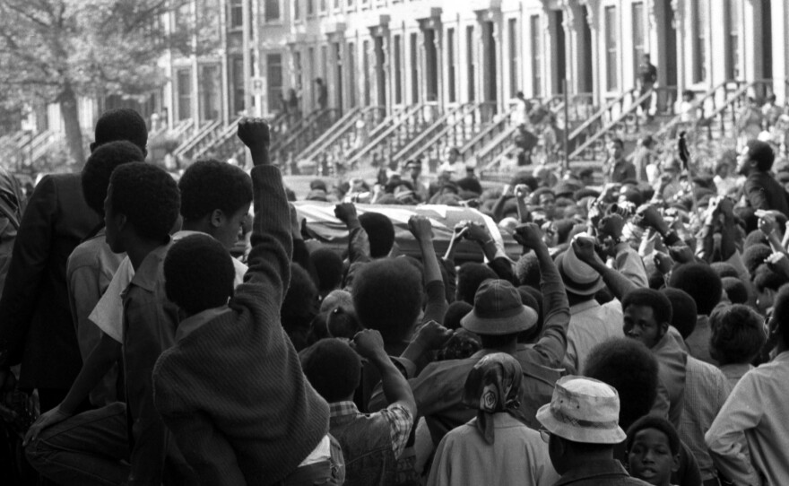 On a Brooklyn street in September 1971, a sea of fists greets the caskets of several of the incarcerated men killed in the violent clash at Attica Correctional Facility that month.