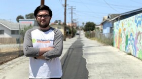 In this undated photo, Climate Action Corps fellow Alex Richter is standing in San Ysidro's historic Cypress Drive, next to a community-made mural.