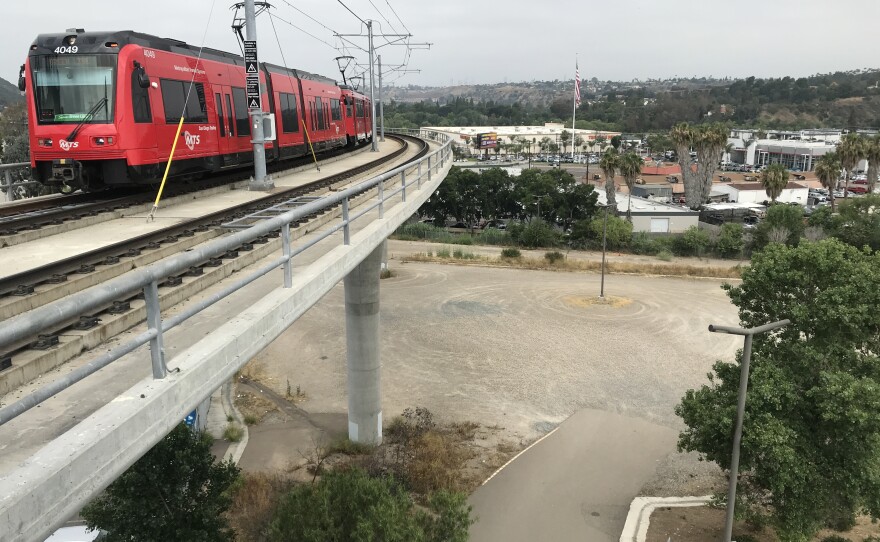 An MTS trolley approaching the Grantville station is seen above a vacant lot, which the transit agency has approved for housing development, June 19, 2019.