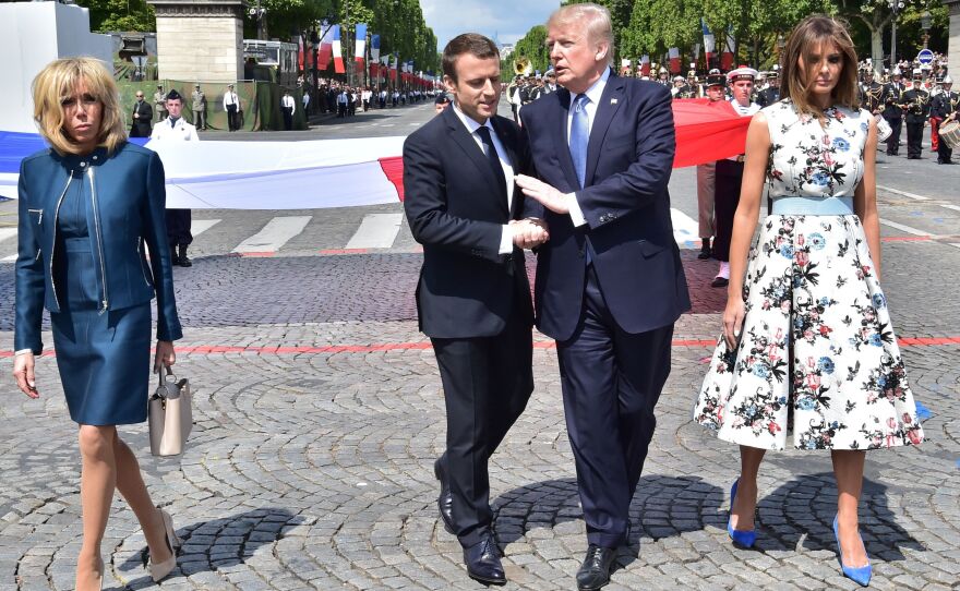 French President Emmanuel Macron and President Trump share a handshake as they walk next to Macron's wife, Brigitte Macron, and U.S. first lady Melania Trump at Friday's Bastille Day parade in Paris.