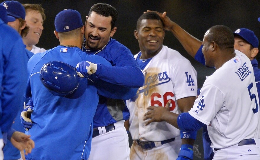 Los Angeles Dodgers' Adrian Gonzalez (center left, holding helmet) is congratulated by teammates along with Yasiel Puig (No. 66) after Gonzalez hit a game-winning RBI double and Puig scored during the 12th inning of their game against the New York Mets on Wednesday.