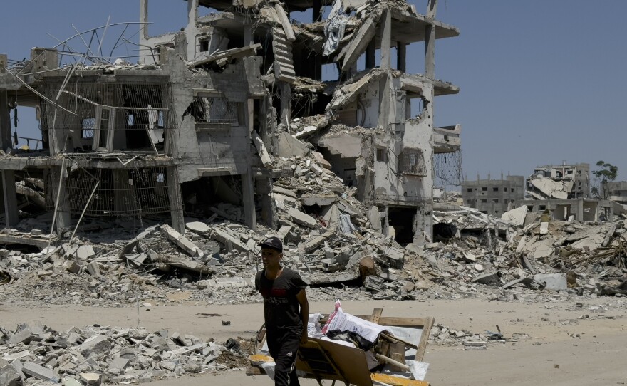 A man lugs items in a makeshift wagon in front of buildings that were bombed out by Israeli strikes in northern Gaza City, Aug. 26.