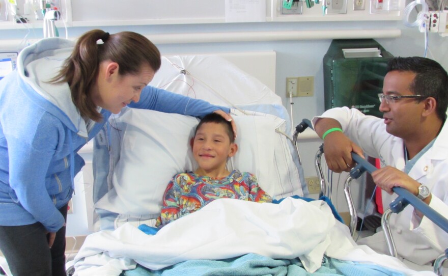 Eric Montaño is shown sitting in a hospital bed while his mother and doctor stand beside him in this undated photo. 