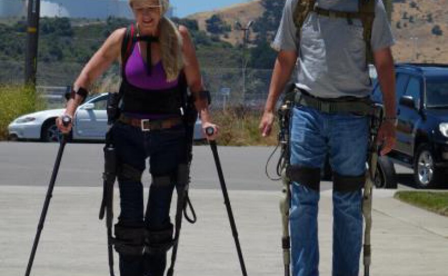 Amanda, a paraplegic who spent 20 years in a wheelchair before this exoskelton allowed her to walk unassisted and David Pogue, wearing a military exoskelton that lets him carry 350 pounds as though it's nothing.