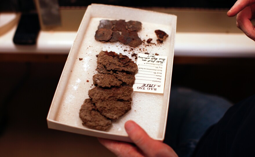 They call it "fried chicken." A lab worker shows a box of old metal that once served as a kind of chain mail for a Jamestown soldier. Each piece is carefully buffed with a wire brush to remove the copious rust.