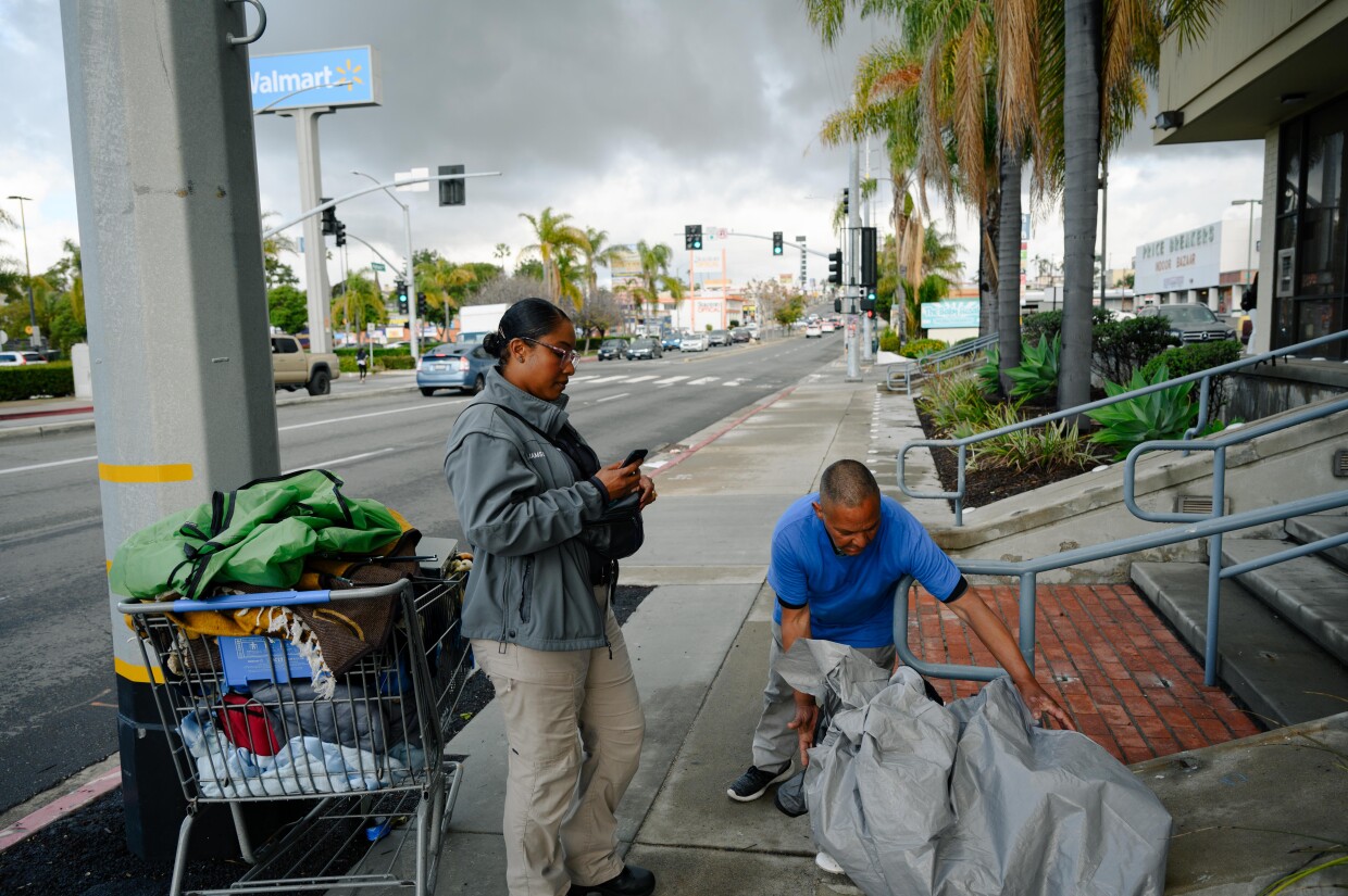 Qiana Williamson, a caseworker with National City’s HOME team, works with Alien Gonzalez, an unhoused resident, to set up an appointment as Gonzalez packs up his tent on Highland Avenue in National City on March 7, 2024. National City is the second in San Diego County to move away from a police-led response to homelessness and toward trained caseworkers.