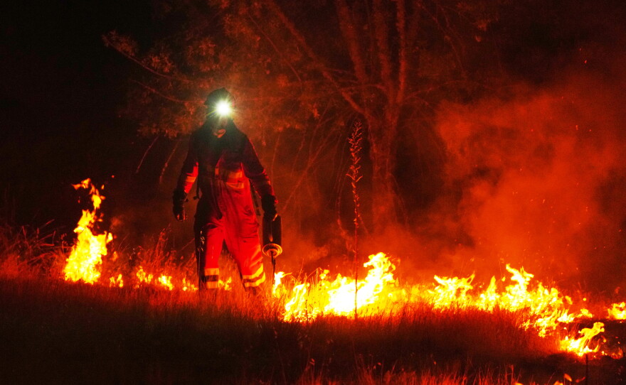 Firefighters use controlled burning to halt a wildfire that continues to spread near Cebreros, Ávila province, Spain, Tuesday, July 28, 2026.