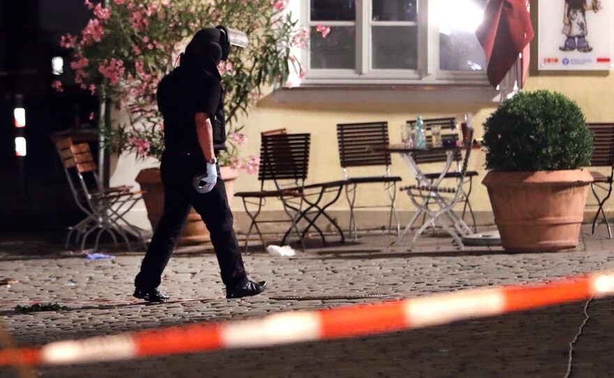 A special police officer examines the scene after an explosion in a public place in Ansbach, Germany, Monday. Bavaria's top security official says a man who blew himself up near an open-air music festival in the southern German city was a 27-year-old Syrian.