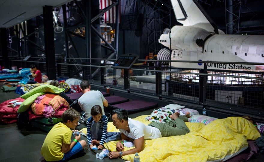 Soraya Okely (center), her dad, Cadeyrn (right), and friend Eli Shroads, 9, examine their handmade satellites before bed.