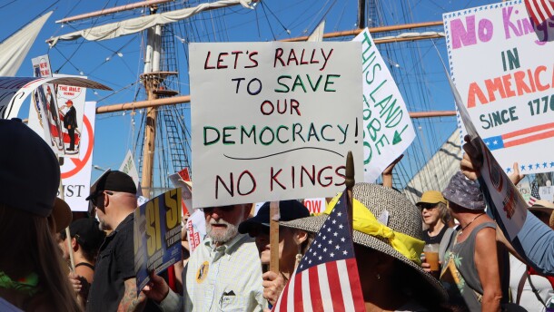 Protestors hold signs during a "No Kings" march on Harbor Drive in San Diego on Saturday, Oct. 18, 2025.