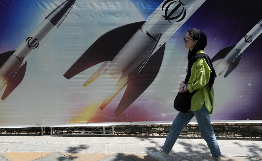 A woman walks past a banner showing missiles being launched, in northern Tehran, Iran, on Friday.