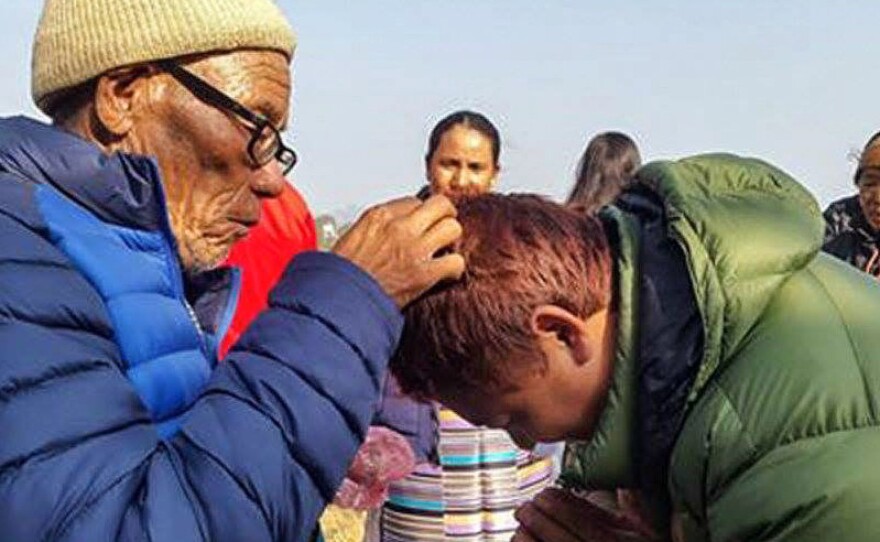 A community elder blesses a man.