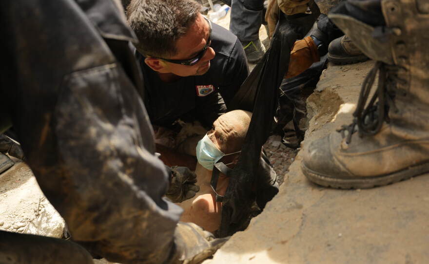 U.S. firefighters from Fairfax County, Va., pull a survivor from the rubble of a building that collapsed in the earthquakes in La Guaira, Venezuela, Sunday.