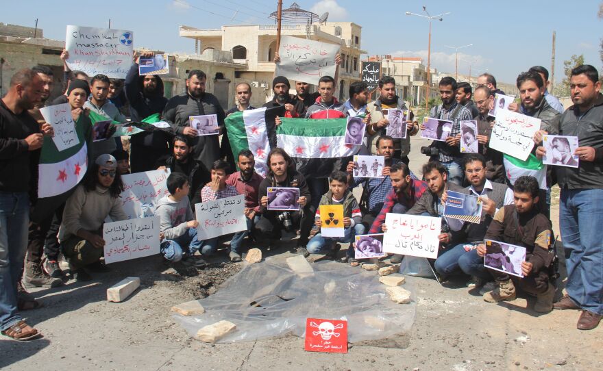 Syrian residents of Khan Shaykhun hold signs and pictures on Friday during a protest condemning a suspected chemical weapons attack on their town earlier this week.