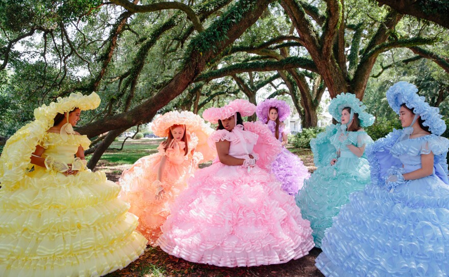 Six of the 50 Azalea Trail Maids gather under oak trees. The dresses come in six different colors, but only the queen of the court wears pink.