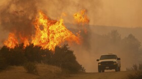 A truck passes by flames during the Ranch Fire in Clearlake Oaks, Calif., on Sunday, Aug. 5, 2018. 