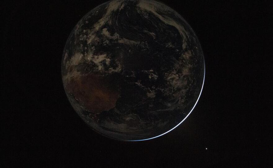 A view of a backlit Earth taken by NASA astronaut and Artemis II Commander Reid Wiseman from one of the Orion spacecraft's window after completing the translunar injection burn on April 2, 2026.