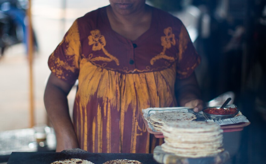 A woman shows how homemade rottis, or coarse, coconut-flecked flat breads, are made.