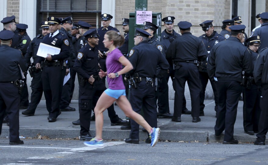 A runner moves past a group of police officers gathered near the finish line of the New York City Marathon on Nov. 6, 2016. Authorities are increasing the number of officers and other law enforcement personnel for this year's race, in the wake of an Tuesday's terrorist attack in the city, in which a truck struck and killed eight bicyclists.