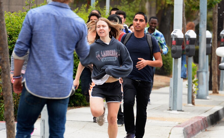 Students rush to safety after shots were fired near the Santa Monica College Friday. According to reports, at least six people were shot, and a suspect was taken into custody. One shooting victim died of her injuries during surgery.