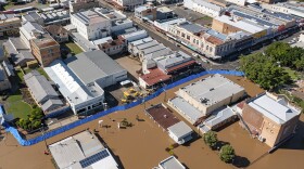 In this photo provided by the Fraser Coast Regional Council, a blue barrier helps hold back flood water in a section of Maryborough, Australia on Tuesday.