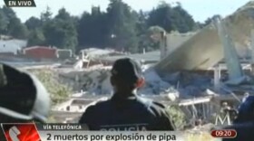 In this video frame grab image taken from Milenio TV, police look at the scene where a gas tank truck exploded outside a maternity and children's hospital in Mexico City, Jan. 29, 2015.