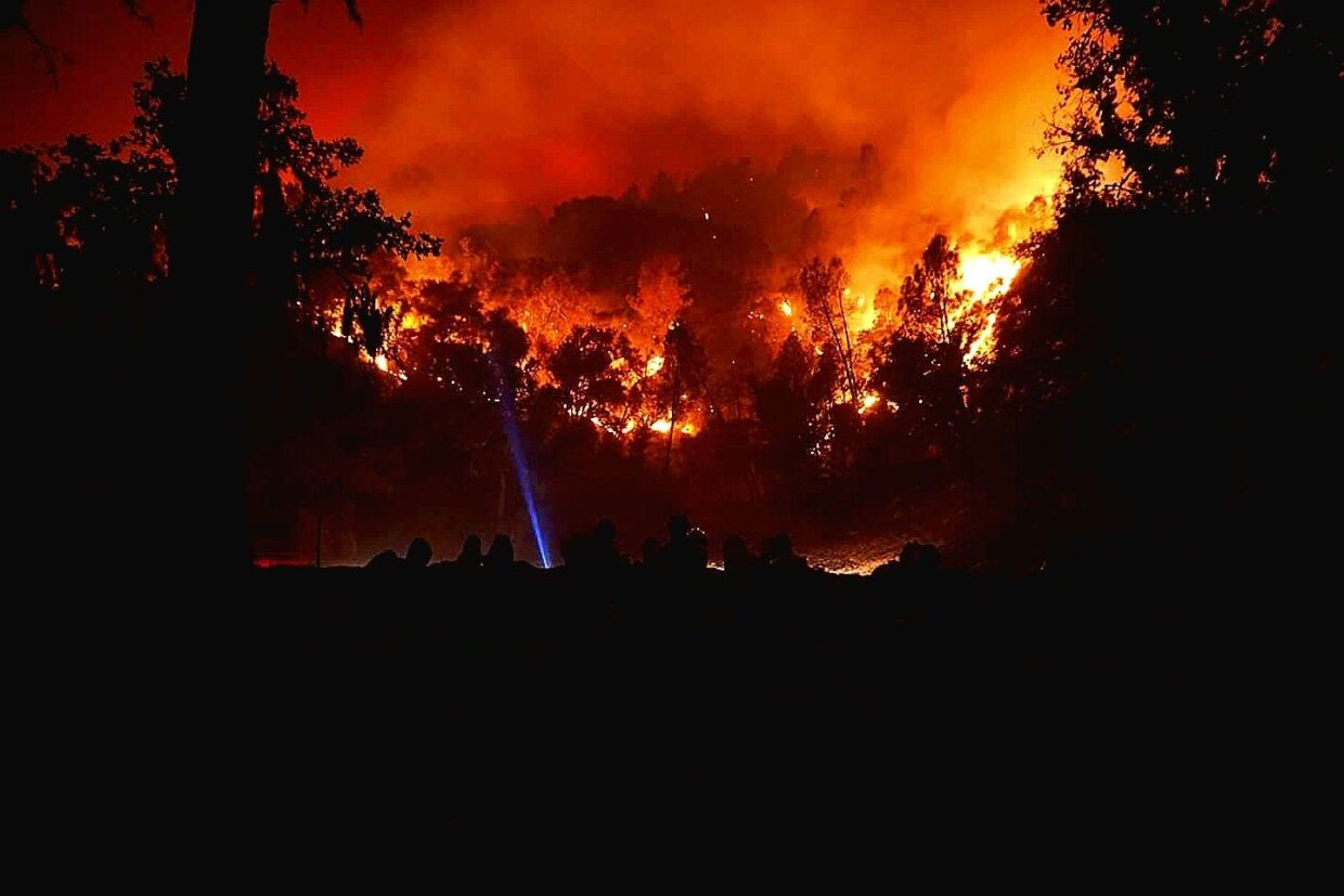 A firefighter turns on their flashlight as a wildfire descends toward them near Fresno, California, in this undated photo.