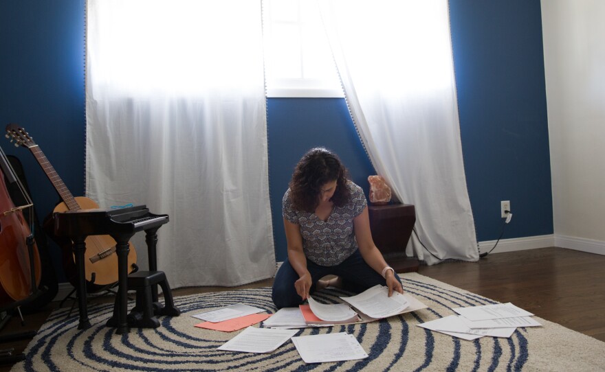 Jeannine sorts through a binder of writing assignments from her therapy. In keeping a journal about her past experiences with pain, she noticed that the pain symptoms began when she was around 8 — a time of escalating family trauma at home.