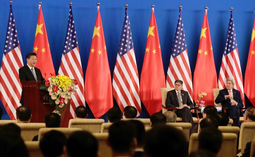 China's President Xi Jinping, left, speaks from the stage with U.S. Secretary of State John Kerry, right, and U.S. Treasury Secretary Jacob Lew, center, during the opening ceremony of the 8th U.S.-China Strategic and Economic Dialogues.