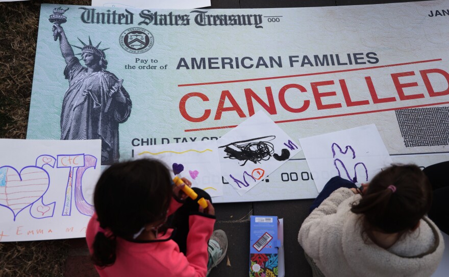 Children draw on top of a canceled check prop during a rally in favor of the child tax credit in front of the U.S. Capitol on Dec. 13, 2021, in Washington, D.C.