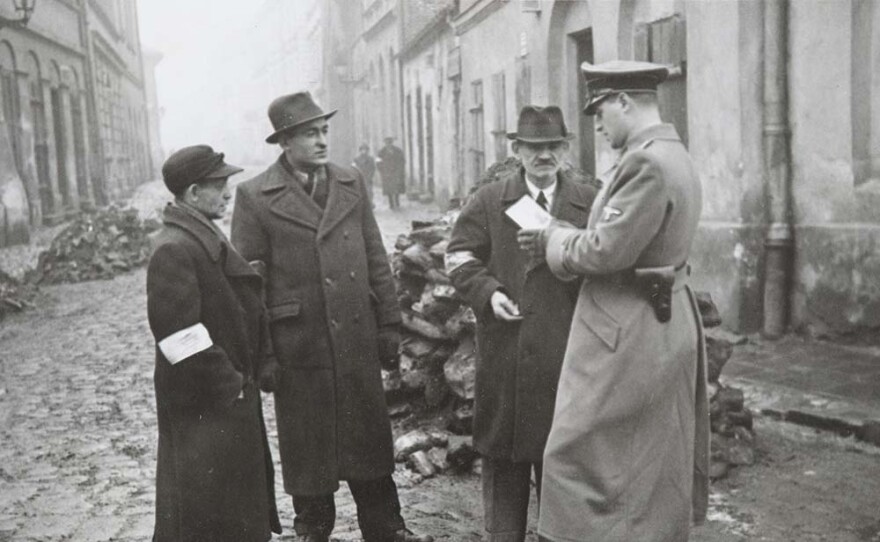 A German policeman checks the identity papers of Jews in the Krakow ghetto. Poland. Around 1941.