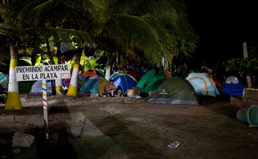 A sign forbids camping on the beach in Necoclí. But hundreds of Haitian migrants camp there each night, waiting to cross the Darién Gap and continue their journey to the U.S.