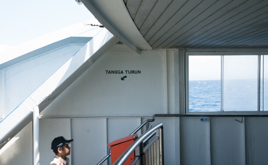 A ferry crew member walks from the truck level to where the passengers sit.