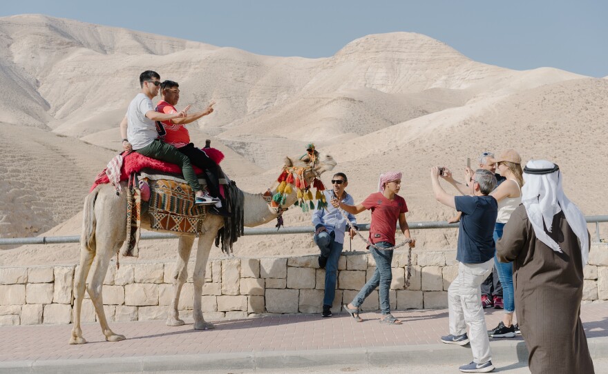 Tourists pose for photographs on camels on the road leading to the Dead Sea in the Israeli-occupied West Bank.