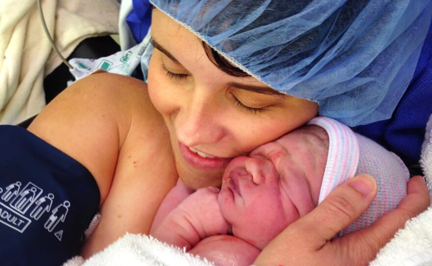 Kristen Caminiti cuddles her son Connor while doctors stitch her up following a C-section.