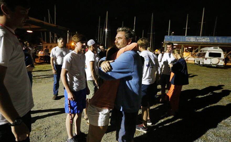 Regatta participant Robert Luiten of Mobile, Ala., right, rejoices on learning that his son, Leonard Luiten, was found after their boat capsized in a storm on Saturday, in Dauphin Island, Ala. The Coast Guard is still searching for four missing sailors.