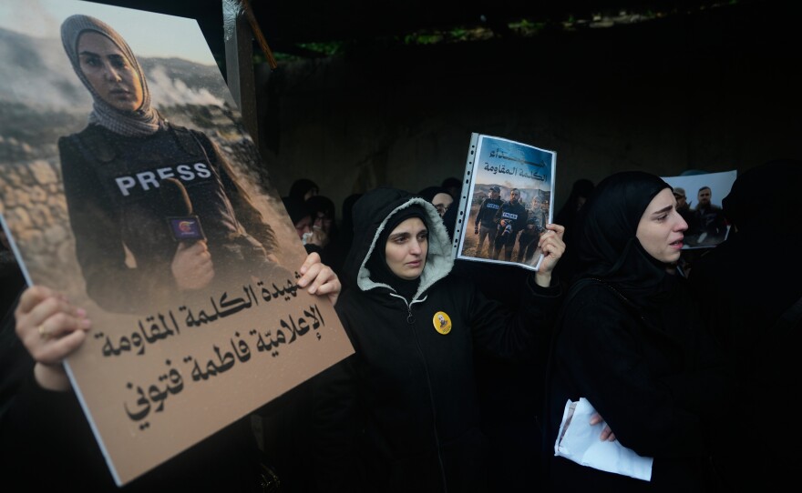Women hold posters showing Al-Mayadeen TV reporter Fatima Ftouni, left, and, in another poster, Hezbollah's Al-Manar TV correspondent Ali Shoeib, center, and cameraman Ali Ftouni during their funeral at a temporary cemetery in Dahiyeh, Beirut's southern suburbs, Beirut, Lebanon, Sunday, March 29, 2026.