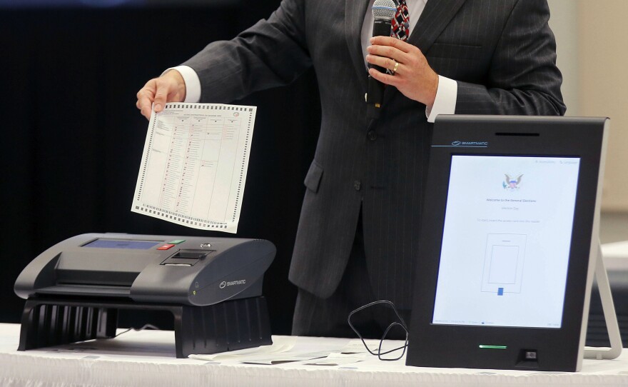 A Smartmatic representative demonstrates his company's system, which has scanners and touch screens with printout options, at a meeting of the Secure, Accessible & Fair Elections Commission, on Aug. 30, 2018, in Grovetown, Ga.