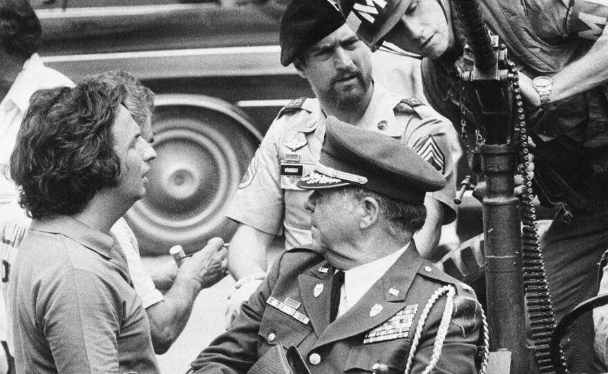 Director Michael Cimino (left) talks with actor Robert De Niro (center wearing beret) during a break while filming The Deer Hunter on location in Bangkok.