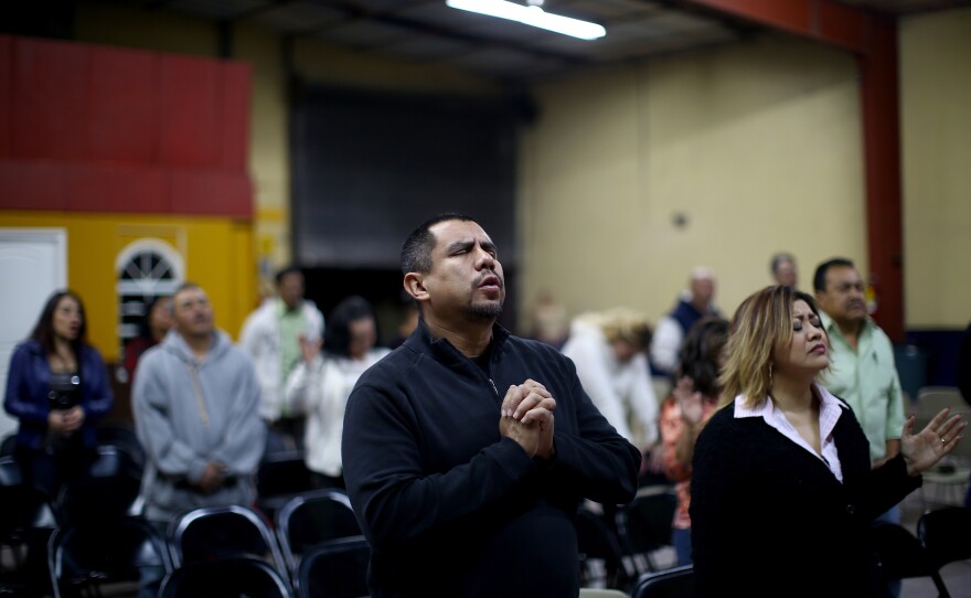 Pastor Robert Salazar (center) prays before giving his sermon at the "Cruising for Jesus" mission of Tijuana. Salazar's church also runs a men's drug-rehab shelter nearby to help deported veterans.