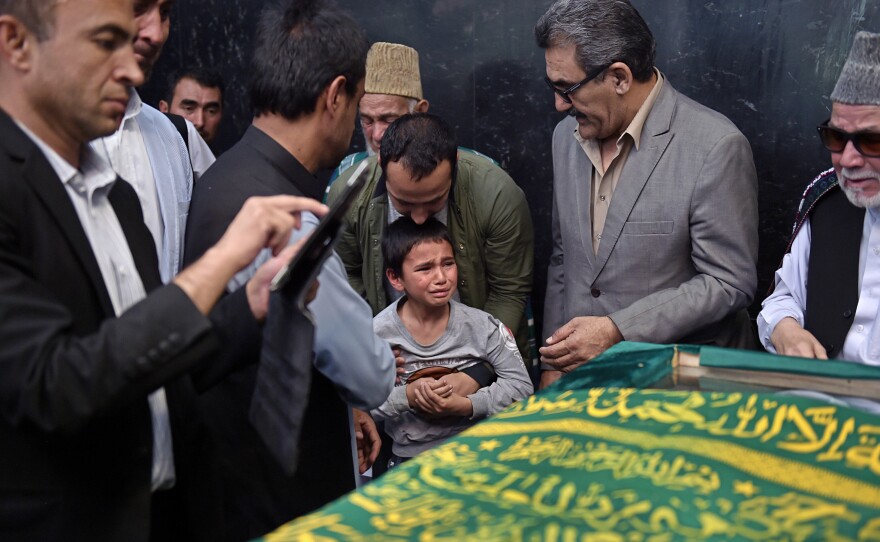 Ten-year-old Mustafa (center), son of Afghan reporter Zabihullah Tamanna, prays with relatives and friends next to the coffin during Tuesday's ceremony.