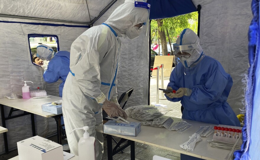 Workers in protective overalls conduct mass COVID testing for residents on May 11, 2022, in Beijing.