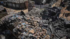 Palestinians walk past a food-aid warehouse damaged in an Israeli airstrike that targeted a nearby house in Deir al-Balah, central Gaza Strip, Wednesday, Aug. 26, 2026.