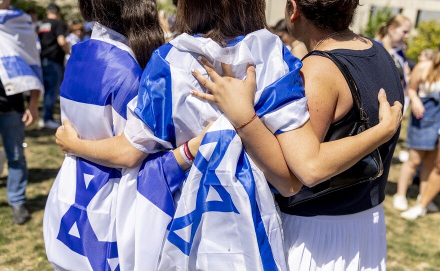 Pro-Israel counter-protestors draped in Israeli flags embrace at George Washington University.