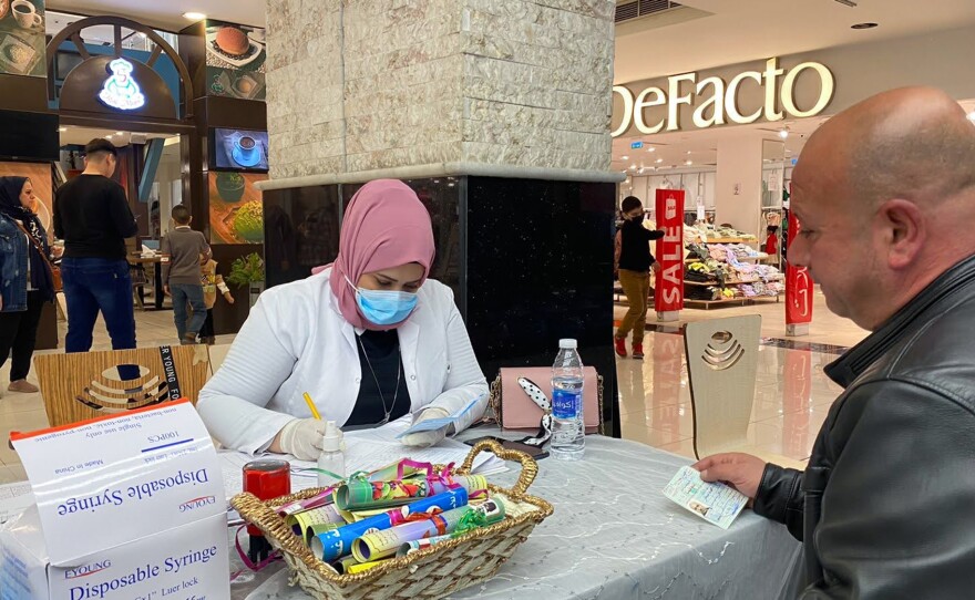A health worker from the Baghdad Health Directorate fills out paperwork at a mobile COVID vaccine clinic in the Zayoona shopping mall in downtown Baghdad.