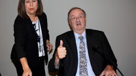 Oceanside Mayor Jim Wood gives a thumbs up before the city council meeting, where he was granted an extension to his medical leave. His council aide, Debbie Walker-Mikulay, is at his side, Oct. 4, 2017.