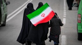 Two women and a child holding an Iranian flag walk toward the Imam Khomeini Grand Mosque to attend Friday prayers in Tehran, Iran, on Friday.