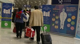 In this Jan. 13, 2020, photo, travelers pass by a health checkpoint before entering immigration at the international airport in Beijing. 