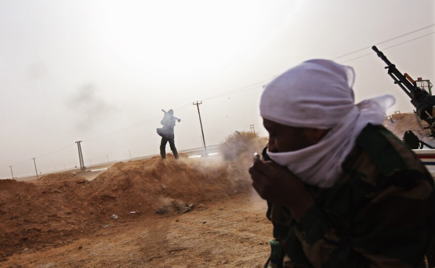 A rebel fires a rocket-propelled grenade from a militia post in Ajdabiya, Libya.